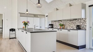 A modern kitchen with a central island, white cabinetry, a tiled backsplash, and a hanging light fixture. - VillaVilla 497 - Mommark, Sydjylland (Sydals)