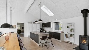 A modern kitchen with a central island, pendant lighting, and a black stove. - VillaVilla 350 - Asserbo/Liseleje, Nordsjælland (Frederiksværk)