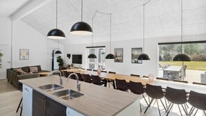 A modern kitchen with a central island, black pendant lights, and a large window overlooking a garden. - VillaVilla 350 - Asserbo/Liseleje, Nordsjælland (Frederiksværk)