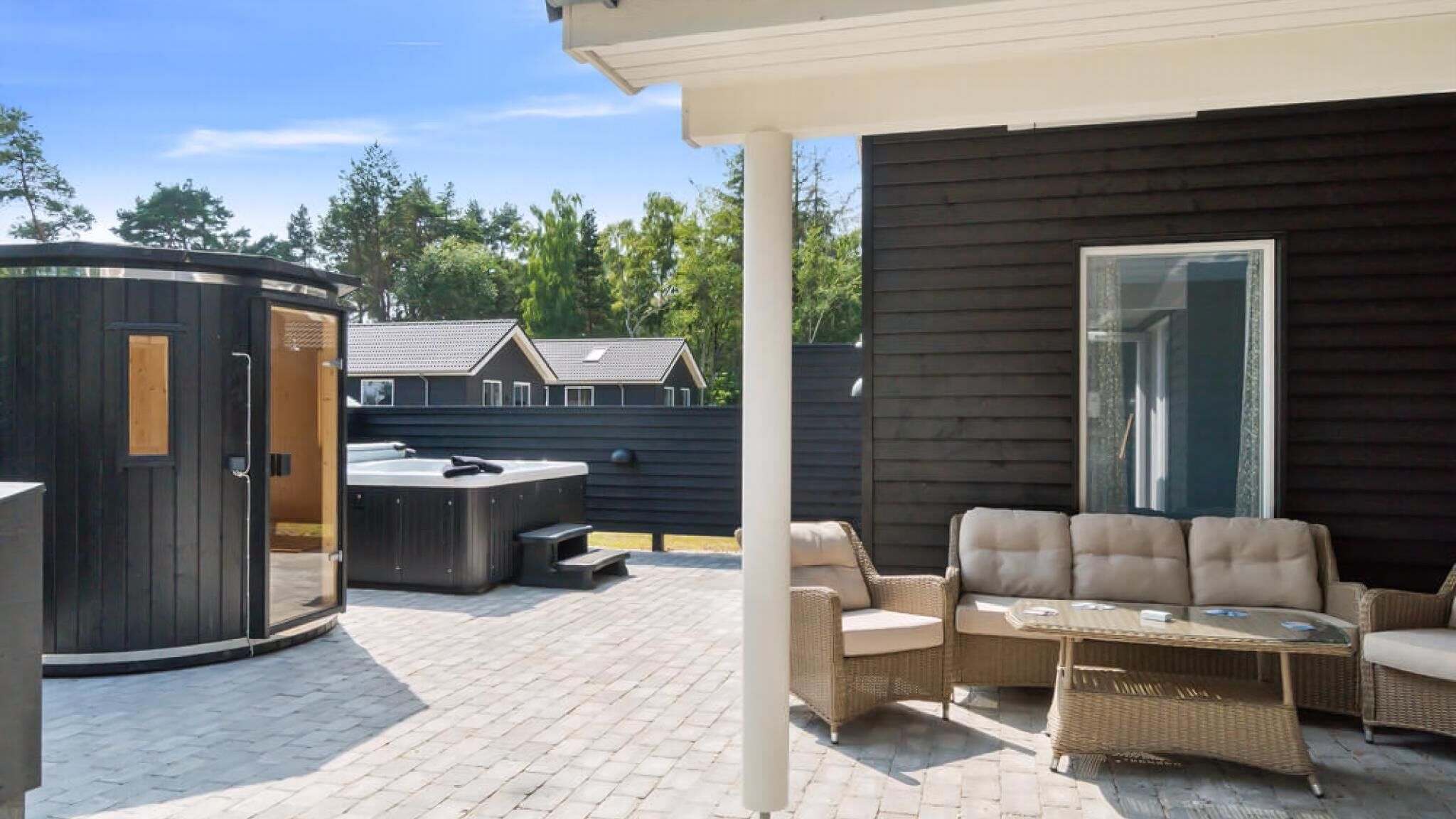 A covered patio with outdoor furniture, a hot tub, and a large water heater.