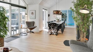A modern interior with a dining area, a grey sofa, and a large window. - VillaVilla 515 - Marielyst, Lolland/Falster/møn (Væggerløse)