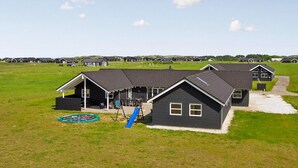 Una hilera de casas modernas de color oscuro con un parque infantil al frente.