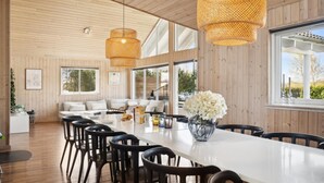 A modern dining area with a long table, black chairs, and a vase of flowers. - VillaVilla 282 - Marielyst, Lolland/Falster/møn (Idestrup)