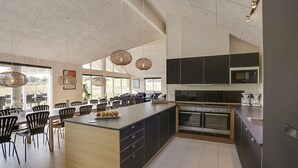 Una cucina moderna con una grande isola, mobili scuri e illuminazione a sospensione.