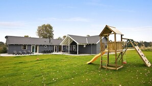 Een gebouw met een overdekte patio, een speeltuin met een glijbaan, en een gazon.