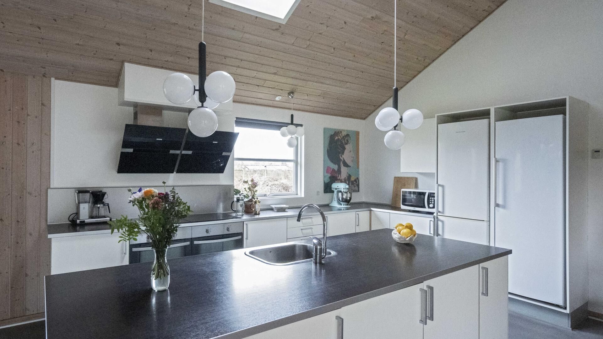 A modern kitchen with a central island, stainless steel appliances, and a wooden ceiling.