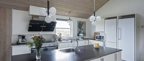 A modern kitchen with a central island, stainless steel appliances, and a wooden ceiling.