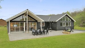 Une maison moderne dotée d’un grand patio, d’un coin repas et d’un barbecue.