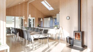 Eine moderne Küche mit Holzwänden, einem Essbereich mit Tisch und Stühlen sowie einem Kaminofen.