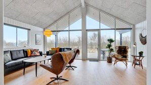Un salon spacieux avec une grande fenêtre, un canapé, une table basse et un fauteuil.