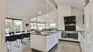 Une cuisine moderne dotée d’un grand îlot central, d’appareils électroménagers intégrés et d’un coin repas avec des chaises.