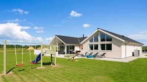 Une maison avec un patio, une balançoire et un toboggan.