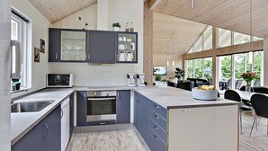A modern kitchen with grey cabinets, a built-in oven, and a large island with a sink. - VillaVilla 321 - Gilleleje, Nordsjælland (Dronningmølle)