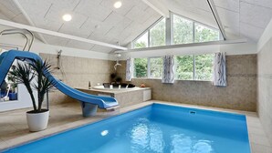 An indoor swimming pool with a slide, a jacuzzi, and a view of greenery outside. - VillaVilla 321 - Gilleleje, Nordsjælland (Dronningmølle)