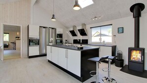 Una cocina moderna con una isla central, electrodomésticos de acero inoxidable y una estufa de leña.