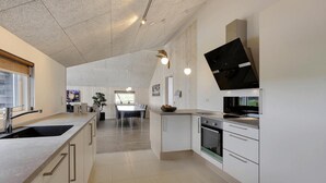 A modern kitchen with a large island, built-in oven, and a flat-screen TV mounted on the wall. - VillaVilla 327 - Faaborg, Fyn og øer (Faaborg)