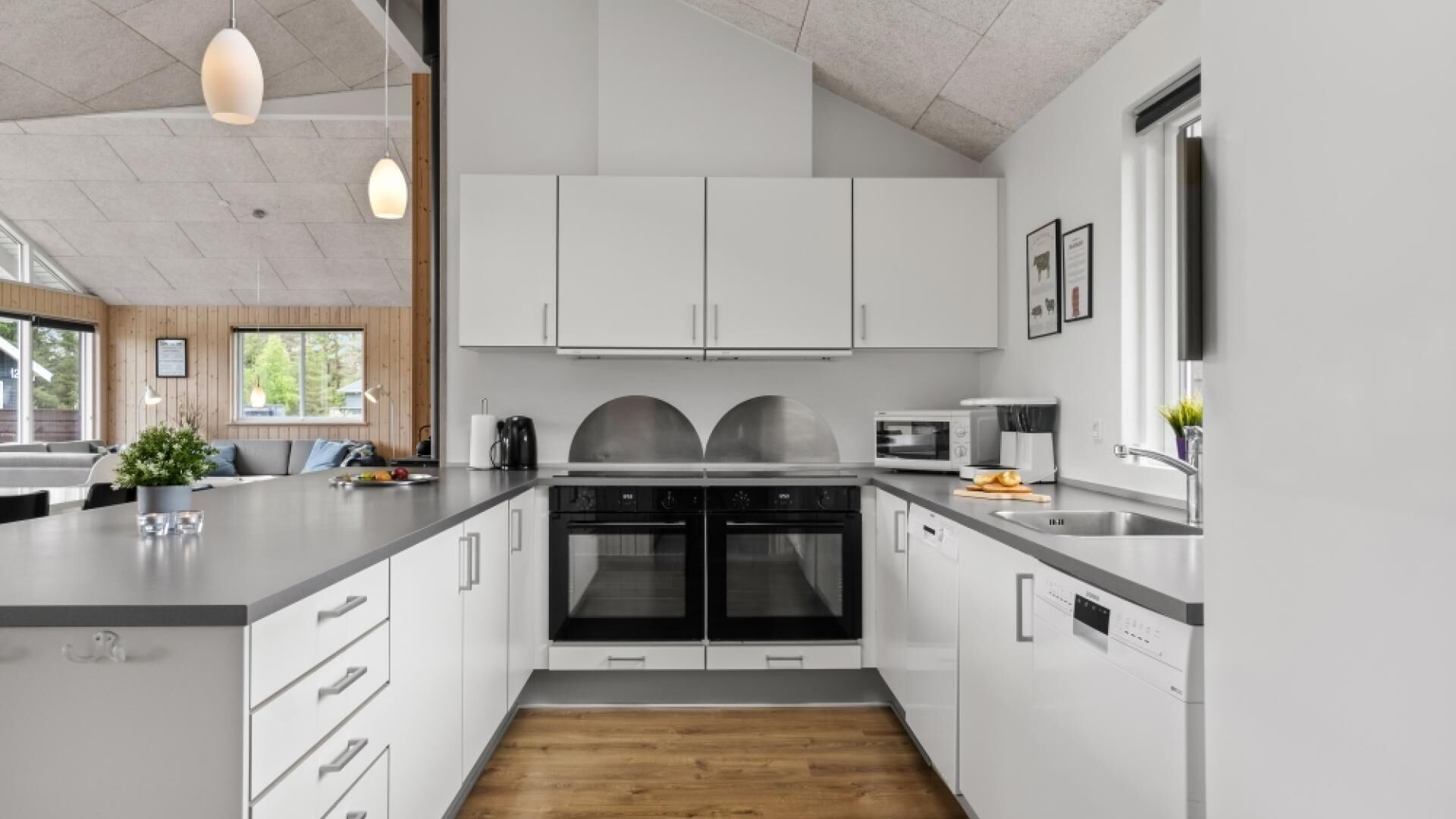 A modern kitchen with white cabinets, a central island, and built-in ovens.