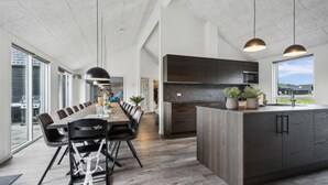 Une cuisine moderne dotée d’un grand îlot central, de meubles en bois foncé et de luminaires suspendus.