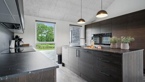 Une cuisine moderne avec des meubles en bois foncé, un plan de travail noir et des luminaires suspendus.