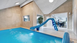 An indoor swimming pool with a blue slide, a view of the outside, and a dining area. - VillaVilla 560 - Houstrup Strand, Vestjylland (Nørre Nebel)