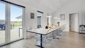 Ein geräumiger Essbereich mit einem langen Tisch, klaren Stühlen und Blick ins Freie.