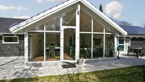 A modern house with a large glass conservatory, a patio with a table and chairs, and a solar panel on the roof. - VillaVilla 312 - Hornbæk, Nordsjælland (Hornbæk)