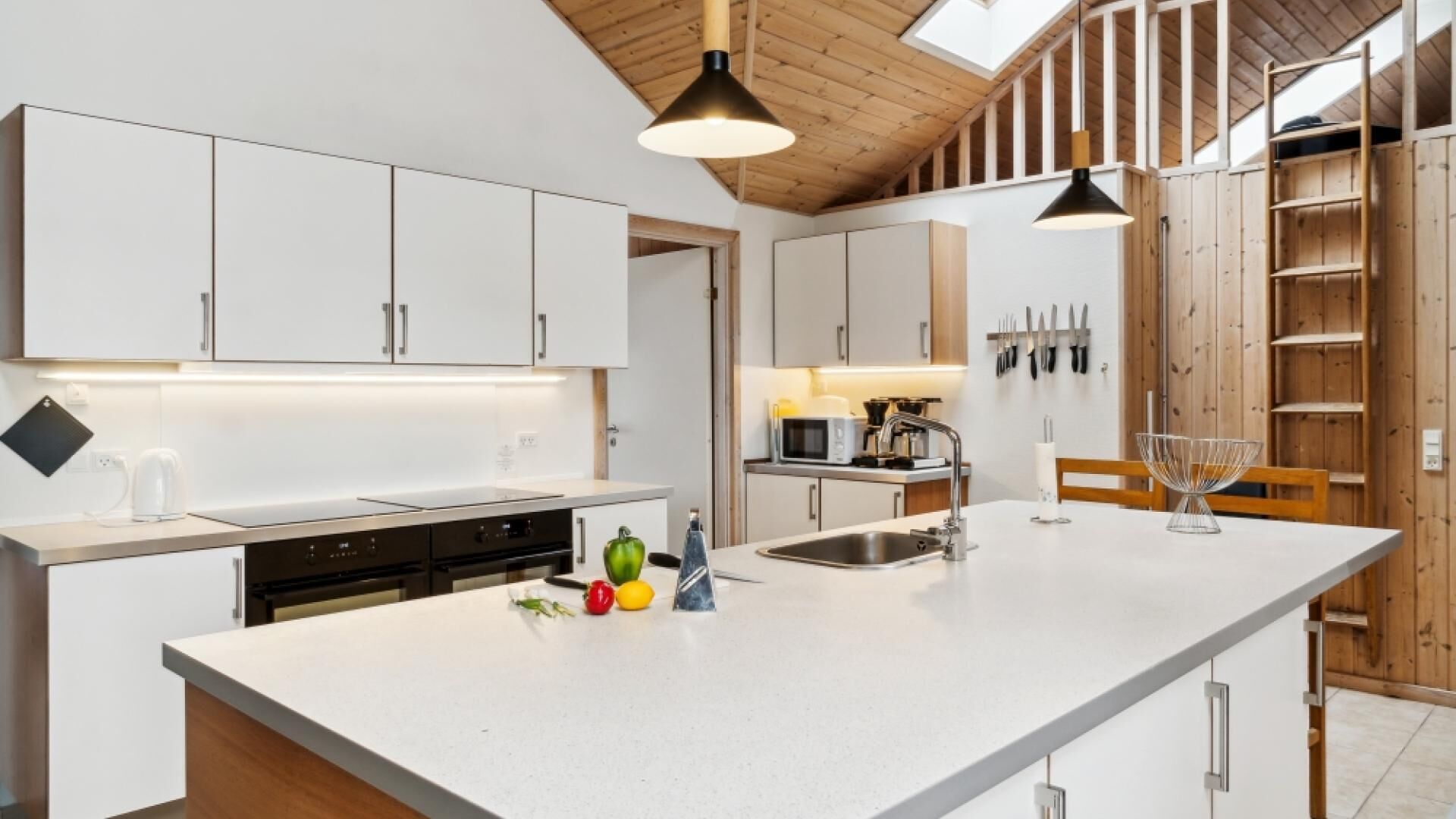 Una cocina moderna con armarios blancos, una isla central y detalles de madera.