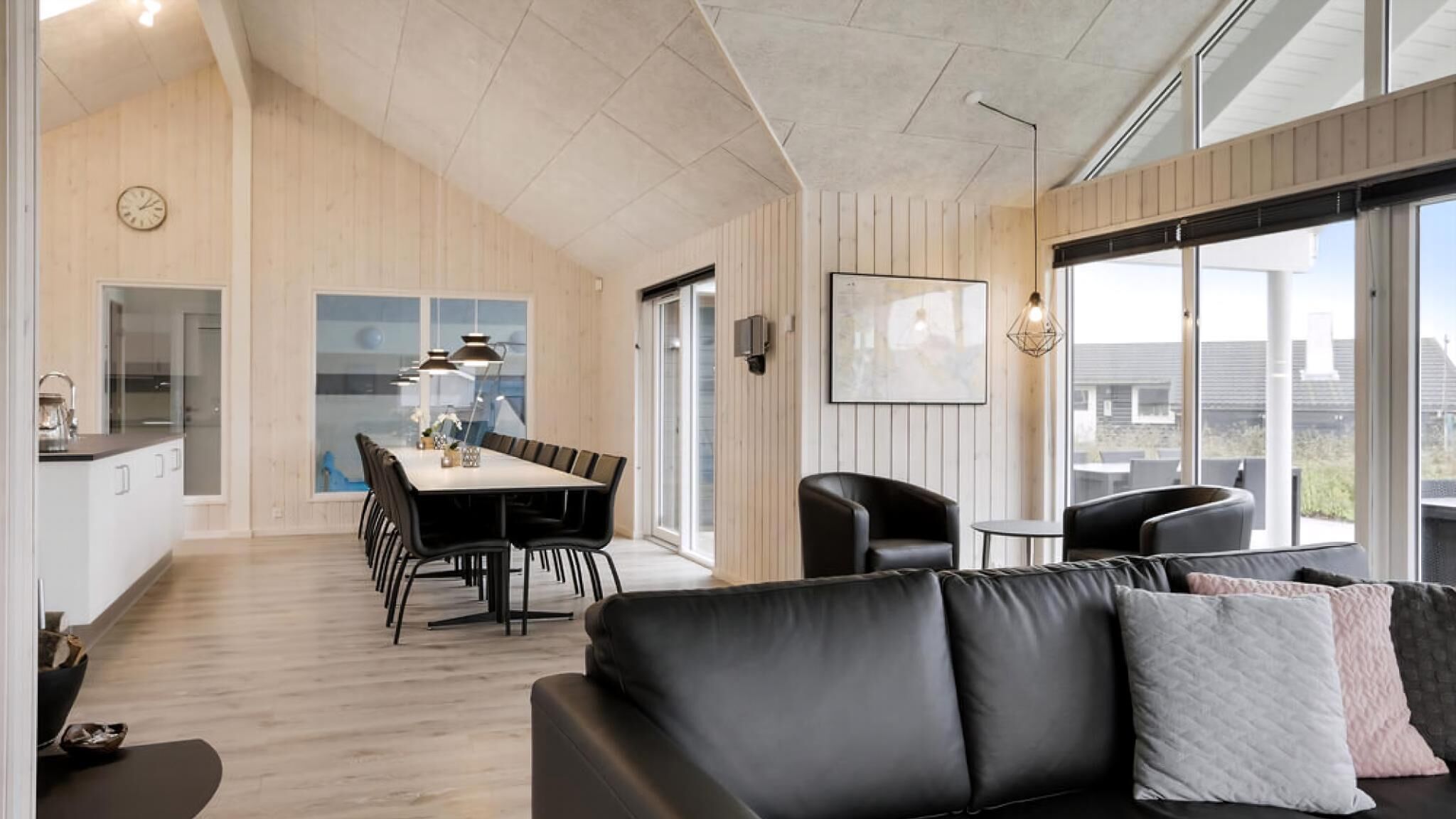 Een modern interieur met een eethoek, een bank en grote ramen.