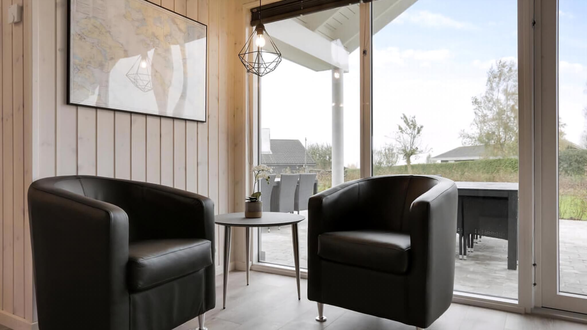 A modern room with two leather chairs, a small round table, and a map on the wall.