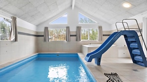Ein Innenpool mit einer blauen Rutsche, einem Fenster und einem Waschbecken.