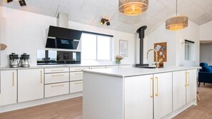 Et moderne køkken med hvide skabe, en central ø og hængende lamper.