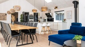 Et moderne køkken med en central ø, sorte stole, en blå sofa og et spisebord.