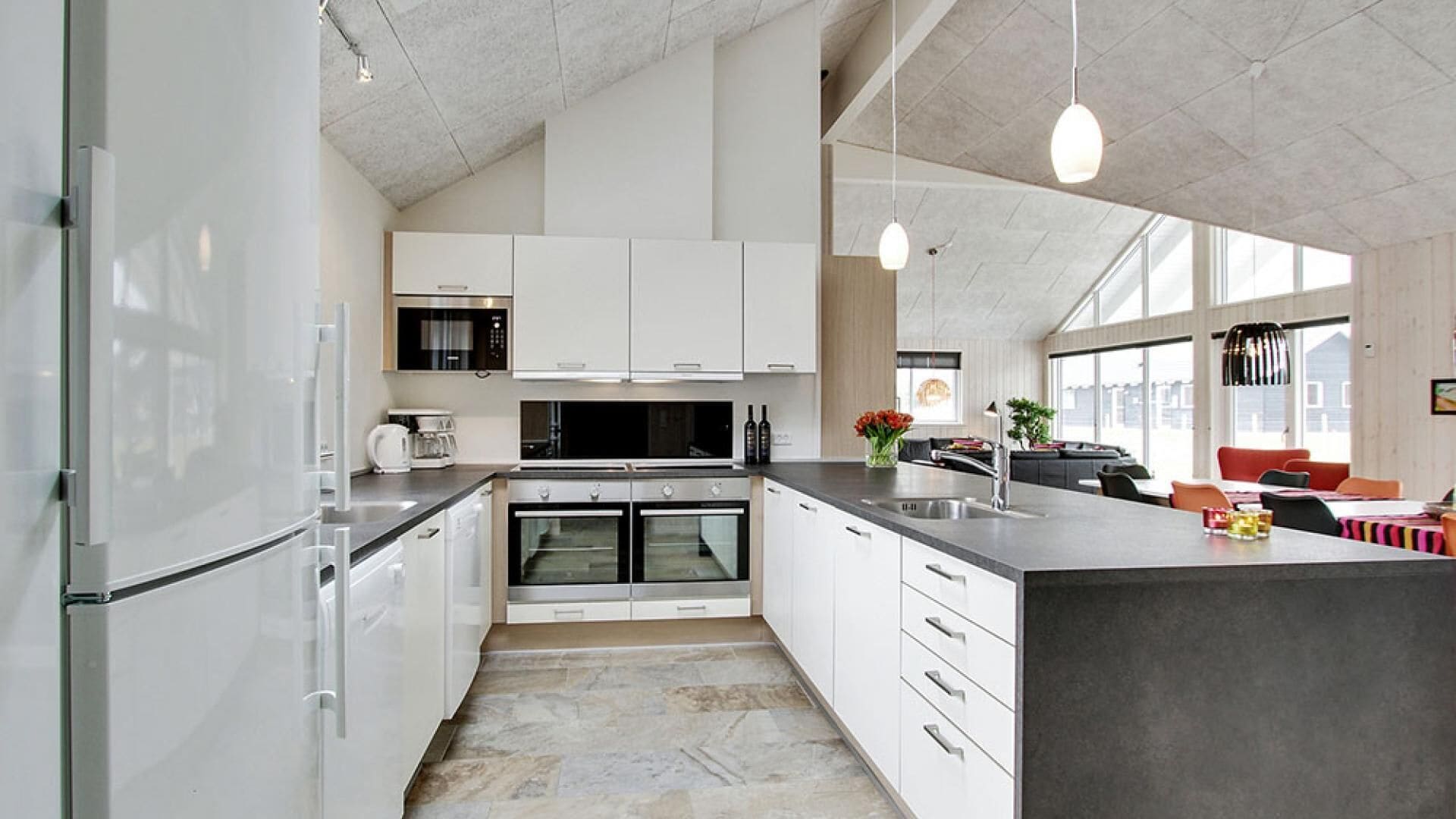 A modern kitchen with white cabinetry, stainless steel appliances, and a large island.