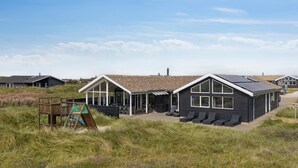 Une maison de plage moderne dotée d’une grande terrasse, d’un espace de jeux et offrant une vue sur la mer.