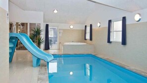 An indoor swimming pool with a blue slide, a bathtub, and a door leading to an outdoor area. - VillaVilla 283 - Vejers, Vestjylland (Vejers Strand)