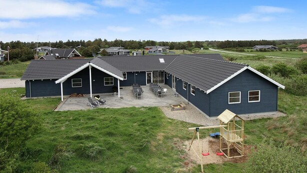 A two-story house with a covered patio, a swing set, and a small play area. - VillaVilla 283 - Vejers, Vestjylland (Vejers Strand)