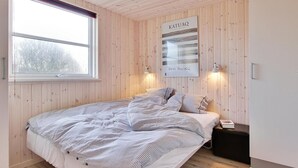 A bedroom with a bed, a nightstand, a window, and a wall-mounted light fixture. - VillaVilla 283 - Vejers, Vestjylland (Vejers Strand)