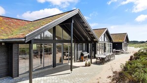 Un bâtiment moderne doté de grandes fenêtres et d’un toit en pente recouvert de végétation.