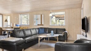 Ein modernes Wohnzimmer mit einem schwarzen Ledersofa, einem Couchtisch und einem an der Wand befestigten Fernseher.
