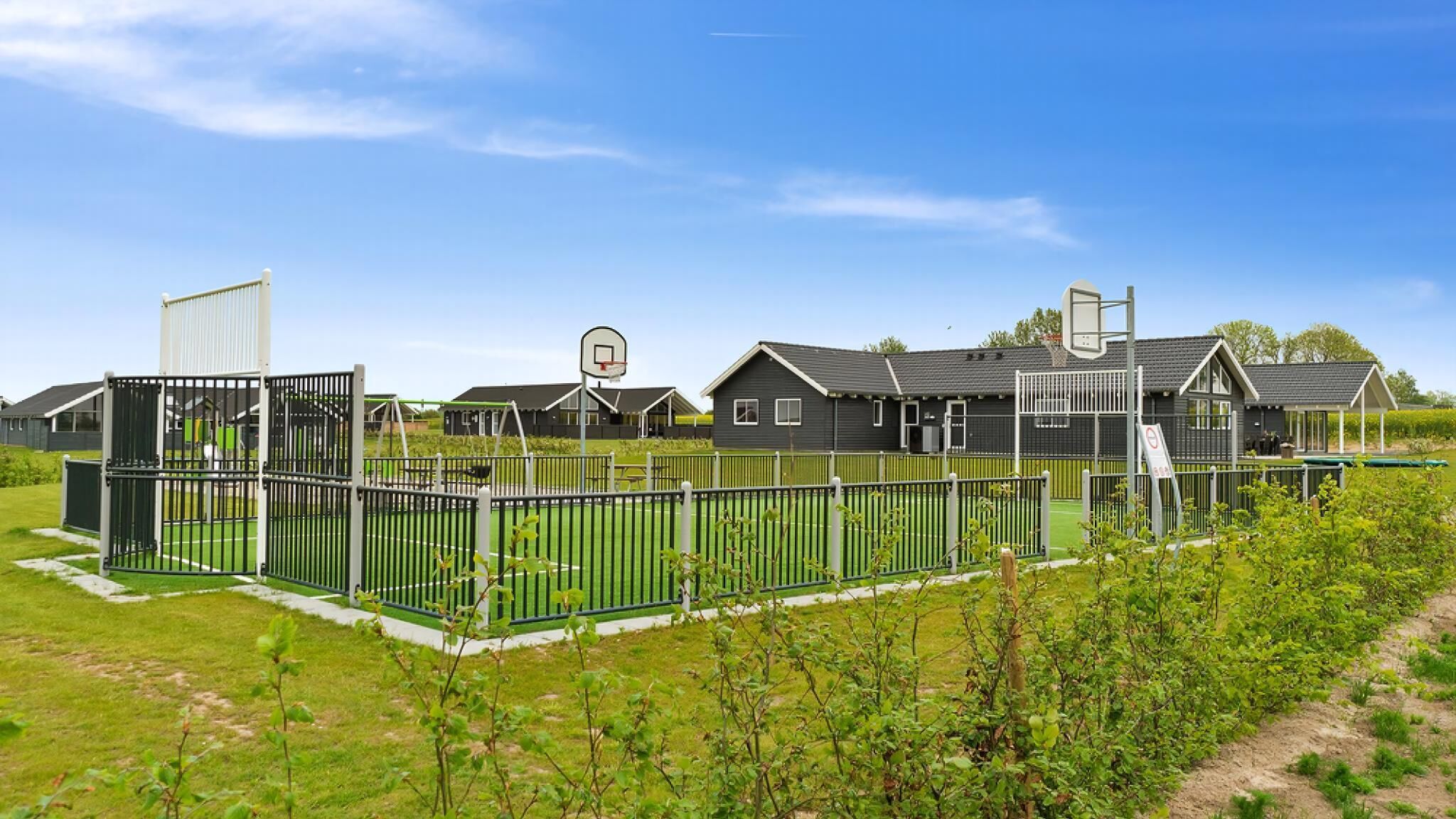 A residential area with multiple houses, a basketball court, and a fenced playground.