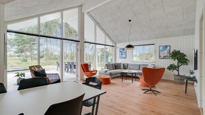 Un salon spacieux doté de grandes fenêtres, un coin repas et un espace salon confortable.