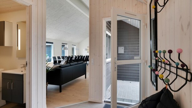 Un interior moderno con un sofá negro, una pared de madera y un perchero con bolas de colores.