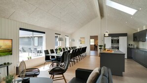 Una cocina amplia con electrodomésticos modernos, un comedor con una mesa larga y sillas, y un rincón de estar acogedor con un sofá y sillones.