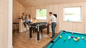 Ein Raum mit Tischfußball, Billardtisch und Barbereich mit Hockern.