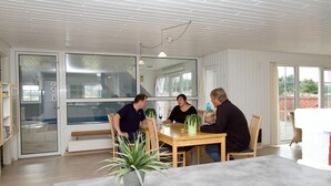 Ein moderner Essbereich mit Holztisch und -stühlen, großen Fenstern und einem Blumentopf.