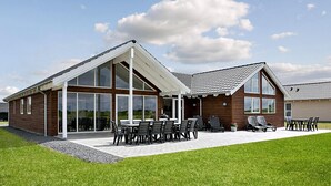 Ein modernes Haus mit einer großen Terrasse, Sitzgelegenheiten im Freien und einem überdachten Bereich.