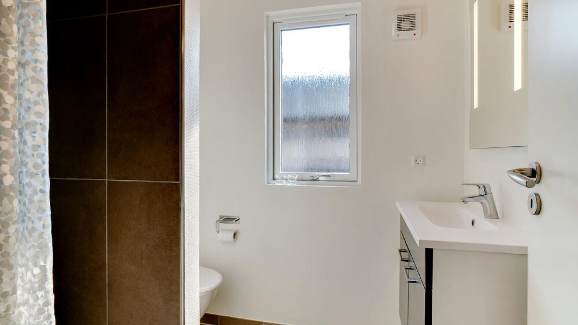 A modern bathroom with a toilet, a sink, and a window.