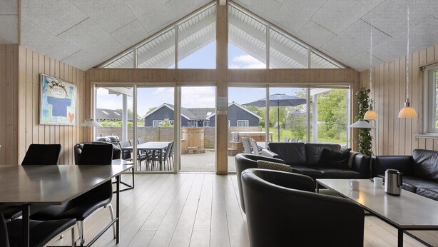 A spacious room with a high ceiling, large windows, a dining area, and a seating area with a sofa and chairs. - VillaVilla 255 - Kegnæs, Sydjylland (Sydals)