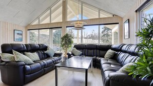 A spacious living room with a high ceiling, large windows, and black leather sofas. - VillaVilla 384 - Gilleleje, Nordsjælland (Græsted)