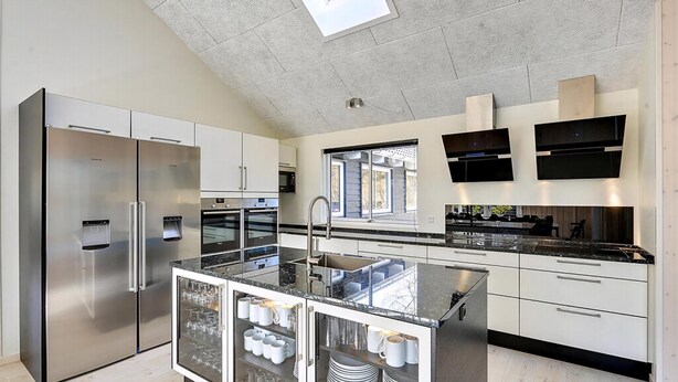 A modern kitchen with stainless steel appliances, a central island with glass storage, and a window providing natural light. - VillaVilla 384 - Gilleleje, Nordsjælland (Græsted)
